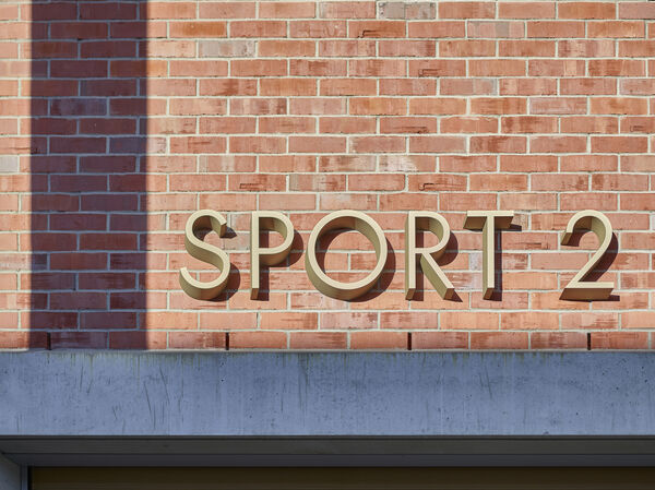 Gebäudebeschriftung ‹Sport 2› der Kantonsschule Ausserschwyzaus eloxiertem Messing
